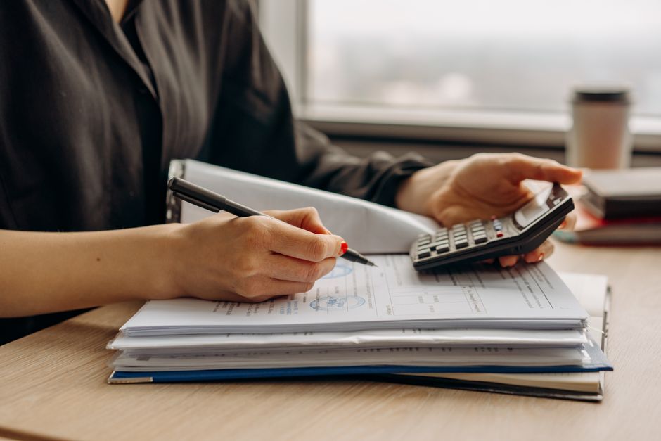 Person using a calculator while working through a small business's financial documents